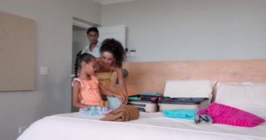 Çeşitli aileler otelde tatil gezisi hazırlıyor, bavullarını gömlek ve havluyla dolduruyorlar. Tatil, toplanma, birliktelik, seyahat, planlama, otel, aile