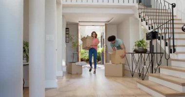 Yeni evlerinde kutuları taşıyarak neşeyle dans eden genç bir çift. Taşınma, kutlama, yeni başlangıçlar, paketleri açma, mutluluk, ilişki