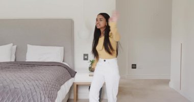 Yatak odasına girdikten sonra kapıyı kapatan, sallanan, yatakta dönüp kutlama yapan bir kadın. Dans, rahatlama, refah, iç mekan, yaşam tarzı, hareket, çağdaş