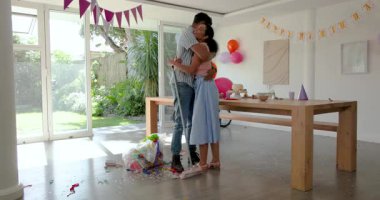 Evde çeşitli çiftler, evde abur cubur, balon, süpürge ve çöp torbasıyla parti veriyor. Kutlama, şenlikli, neşeli, dekor, toplanma, mutluluk, parti