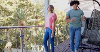 Genç bir adam balkonda evlenme teklif ediyor, kadın şaşırmış ve evde ağzıyla kapatıyormuş. Romantizm, nişan, evlenme teklifi, aşk, çift, ilişki