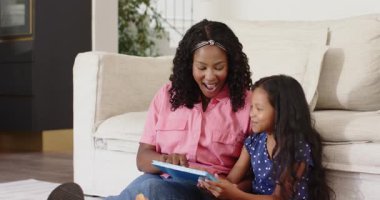 Anne ve kızı evde, sıcak oturma odasında masal kitabı okuyorlar. Çeşitli aile, bağ, çocukluk, hikaye anlatma, ebeveynlik, ev