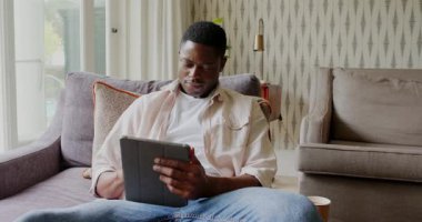 Kanepede oturan Afro-Amerikalı bir adam, pencereye bakarken durup kahvesini yudumluyor. Rahatlık, rahatlık, rahatlık, modern, konfor, yaşam tarzı, içgözlem