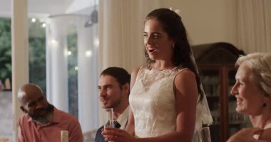 Mum ışığında yükselen gelin, konuklar alkışlarken ve flüt tokuştururken kadeh kaldırıyor. Düğün, kutlama, zarafet, neşe, sofistike, romantizm, neşe