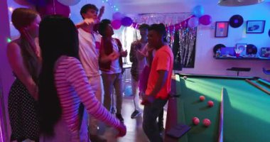 Çeşitli arkadaşlar bilardo masasına çubuk sallayarak beyaz tanktaki dostlarını karşılıyorlar. Kutlama, gece hayatı, canlı, sosyal, eğlence, enerjik, renkli