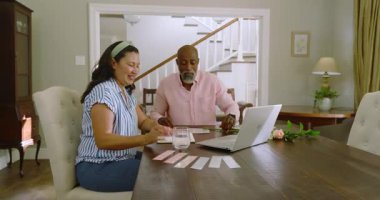 Evrakları evde tartışıyor, kadın ve erkek işbirliği yapıyor, gülümsüyor. İşbirliği, takım çalışması, toplantı, iş, beyin fırtınası, ortaklık