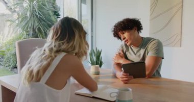 Evde tablet ve defter kullanırken planları tartışan genç bir çift. teknoloji, planlama, dijital, yaşam tarzı, takım çalışması, beyin fırtınası