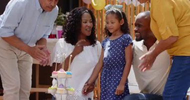 Doğumgününü kutluyoruz, çeşitli aileler evde, açık hava toplantısı sırasında keklerin üzerinde mum yakıyor. Kutlama, açık hava, gelenek, mutluluk, neşe, birliktelik