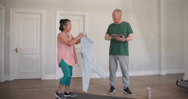 Yaşlı çift evde egzersiz yapıyor, yoga minderi kullanıyor ve mezura kullanıyor, aktif kalıyorlar. Sağlık, fitness, yaşlılık, sağlık, esneme, yaşam tarzı