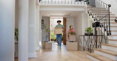 Yeni evlerinde kucaklaşan, kutuları taşıyan, neşeli genç bir çift. Yer değiştirme, mutluluk, paketleri açma, ev sahipliği, yaşam tarzı, kutlama
