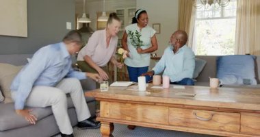 Farklı yaşlılar sohbetten zevk alıyor ve evdeki rahat oturma odasında çiçeklerini değiş tokuş ediyorlar. Yaşlılar, etkileşim, yaşam tarzı, arkadaşlık, rahatlama, hediye