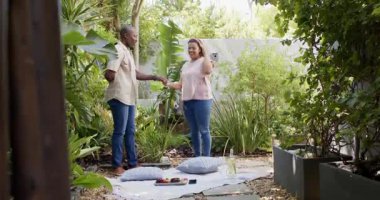 Çeşitli çiftler yemyeşil bahçede piknikten zevk alıyorlar, ellerinde çiçekler ve gülümsüyorlar. Mutluluk, romantizm, doğa, yaşam tarzı, rahatlık