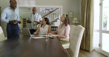 Çeşitli yaşlılar evde kutlama yapıyor, hediye kutusunu açıyor ve yemek masasında gülümsüyor. Çeşitli yaşlılar, kutlamalar, birliktelik, şenlik, kahkaha, mutluluk