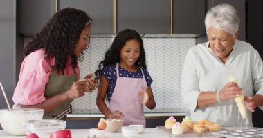 Mutfaktaki kekleri süslemek, farklı ailelerden gelen büyükanneler evde yemek pişirme anlarını paylaşmak. tatlı, çeşitli nesiller, ev, mutluluk, mutfak