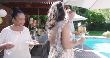 Havuz başında, çeşitli yaşlılar bahçede yemek ve içeceklerle gülüp sohbet ediyor. Rahatlama, sosyalleşme, topluluk, eğlence, parti, emeklilik