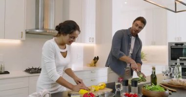 Mutfak adasında biber ve salatalık doğrayan çift, sabit kalıp suyu yudumladıktan sonra gülümsüyor. Aşçılık, mutfak, hazırlık, takım çalışması, konforlu, çağdaş, sevgi