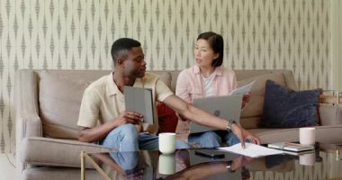 Çeşitli çiftler incelenmek üzere evrak dağıtırken kadınlar da kanepede dizüstü bilgisayarda yazı yazıyor. İşbirliği, takım çalışması, iletişim, dijital cihazlar, ev ofisi, modern yaşam tarzı, bağlantı