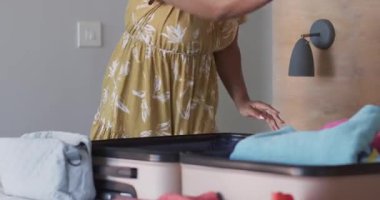 Çeşitli arkadaşlar renkli kıyafetlerini bavula doldurup evde seyahat macerasına hazırlanıyorlar. tatil, yolculuk, valiz, arkadaşlık