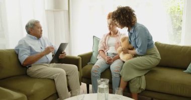 Eşcinsel lezbiyen çeşitliliği olan çift evdeki yeşil kanepede terapistle gülüp sohbet ediyor. LGBTQ, danışmanlık, terapi, destek, çeşitlilik, iletişim