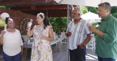 Farklı yaşlılar güneşli gökyüzünün altında bahçe kutlamalarında birlikte içki içiyorlar. Bahçede, içeceklerde, partide, birlikte, gün ışığında, yaşam tarzında