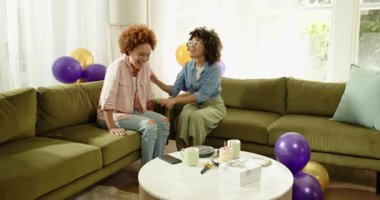 Eşcinsel lezbiyen çeşitliliği olan çift evde doğum gününü kutluyor balonlarla ve pastayla selfie çekiyorlar. Kutlama, parti, mutluluk, yıldönümü, lgbt, ilişki