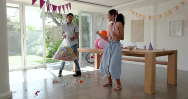 Çeşitli çiftler doğum günü partisinde yerleri süpürüyor, süpürge kullanıyor, konfeti temizliyor, masada, evde. Kutlama, temizlik, coşku, şenlik, takım çalışması, toplanma, dekorasyon