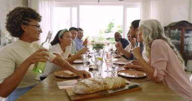 Kıvırcık saçlı kadın şarap doldurduktan sonra çeşitli aile alkışı ve yemek masasının etrafında kadeh kaldırma. Kutlama, neşe, birlik, sıcak, kırsal, jenerasyonel, birliktelik