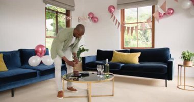 Süslü oturma odasında duran adam evde doğum günü kutlaması için hazırlanıyor. Parti, şenlik, dekorasyon, balonlar, mutluluk, neşe