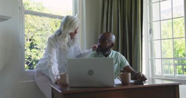 Masada çalışan yaşlı çift, dizüstü bilgisayarda eğilip akıllı telefonlara rehberlik ediyor. Son sınıf, teknoloji, öğrenme, işbirliği, ev, doğal ışık, yaşam tarzı