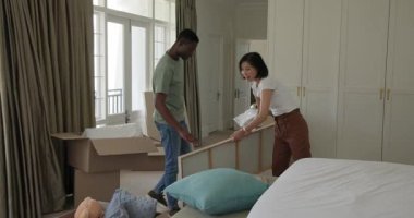 Yatak odasına taşınmak, çeşitli çiftler kutuları ve yastıkları açmak, odayı dekore etmek için resim asmak. Konut, iç mekan, konforlu, çağdaş, yaşam tarzı, tasarım, uyum