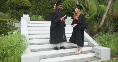 Çeşitli mezunlar basamaklara inip, el sıkışarak ve diplomalarını tutarak dönüm noktalarını belirliyorlar. Kutlama, başarı, akademi, arkadaşlık, açık hava, coşku, başarı