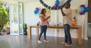 Balonlarla süslü bir odada, farklı çiftler doğum günü pastalarını değiş tokuş ediyor ve gülümsüyor, evde. Kutlama, mutluluk, parti, hediye, bayram, etkinlik