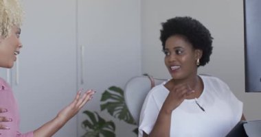 İki kadın akıllı telefon ve tablet kullanıyor, ofiste konuşmaktan zevk alıyorlar. Teknoloji, iletişim, dijital, bağlantı, gündelik, sohbet