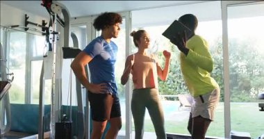 Afro-Amerikalı bir adam spor salonundaki arkadaşlarına tablet gösteriyor, gülümsüyor. Fitness, teknoloji, arkadaşlık, grup, egzersiz, iletişim