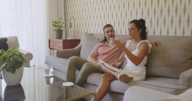 Oturma odasına su taşıyan bir çift girer ve kanepede notları incelerken bir tane de içecek ikram eder. Romantik, samimi, işbirliği, iletişim, modern, yaşam tarzı, iç mekan