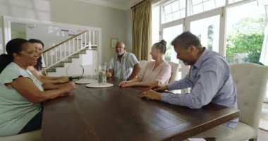 Evde toplanıyorlar, kıdemli çeşitli arkadaşlar yemek masasının etrafında sohbet edip gülüyorlar. Arkadaşlık, birliktelik, neşe, kıdemli yaşam tarzı, kutlama, arkadaşlık.