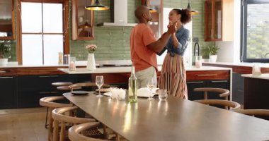 Çeşitli çiftler modern mutfakta neşeyle dans ediyor, evde birlikte özel bir anı kutluyorlar. Aşk, aşk, kutlama, mutluluk, ev, yaşam tarzı