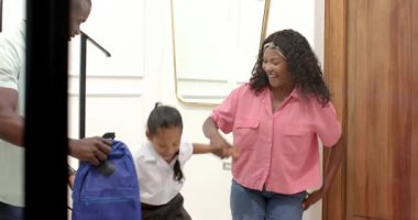 Anne, okula gitmeden önce okul üniformalı kızını cesaretlendiriyor. Ebeveynlik, eğitim, çeşitli aileler, teşvik, destek, sabah rutini