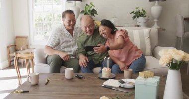 Asyalı yaşlılar doğum gününü evde kutluyor, son sınıf kadın pastaya mum üflüyor. Kutlama, mutluluk, gülümseme, parti, toplanma