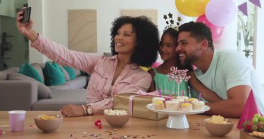 Çeşitli aileler doğum günü kutluyor, evde kek ve hediyelerle selfie çekiyorlar. Kutlama, mutluluk, birliktelik, neşe