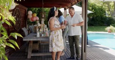 Arka bahçede kutlama, çeşitli gruplar havuz başı partisinde içkilerin ve kahkahaların tadını çıkarıyor. Kutlama, dostluk, yaz, çok kültürlü, toplama, içecekler