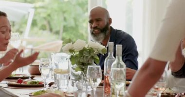 Çeşitli aile kadehlerini kadehleriyle kaldırıyor. Sonra da yemek odasında el kaldırıyor. Kopya odası. Aile, kutlama, neşe, etkileşim, ev, birliktelik, sıcaklık.