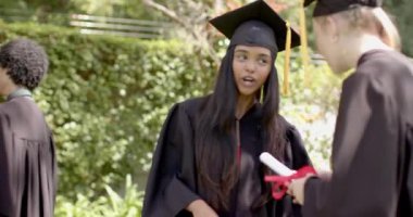 Çeşitli sınıf arkadaşları ağacın altına akıllı telefon çekiyor ve mezuniyet özçekimi için ışıldıyor. Tören, kutlama, yoldaşlık, başarı, birlik, açık hava, gençlik