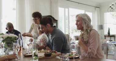 Masada çeşitli aileler ekmek dağıtırken, salata keserken kahkaha atarken ve yaşlı bir kadın tost teklif ederken. Kutlama, birliktelik, neşe, karmaşıklık, sıcaklık, rahatlık, sosyalleşme.