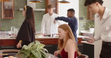 Kıvırcık saçlı adam, kızıl saçlı kadına akıllı telefon uzatıyor. Mutfakta, fotokopi odasında şaşırmış bir şekilde tepki veriyor. Sosyal toplanma, arkadaşlık, modern ev, gündelik yemek, yaşam tarzı, canlı, neşeli