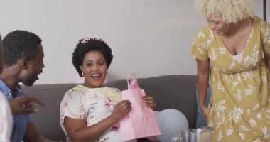 Çeşitli arkadaşlar evde kutlama yapıyor, kadın hediyesini heyecan ve neşeyle açıyor. Kutlama, dostluk, mutluluk, hediyeler, sürpriz, şenlikler