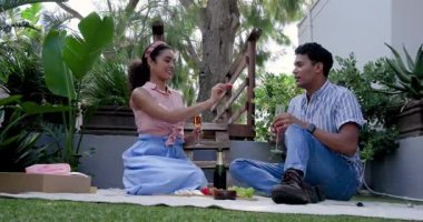 Çeşitli çiftler bahçede çimlerin üzerinde kutlama yapıyorlar. Şampanya ve meyveyle battaniyeyle besleniyorlar. Kutlama, piknik, romantizm, açık hava, mutluluk, doğa, bağlılık, neşe