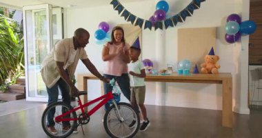 Doğum günü kutlaması, farklı ailelerin çocuklarına evde yeni bir bisiklet vermesi, birlikte gülümsemeleri. Kutlama, mutluluk, hediye, çocukluk, bayram, hediye