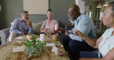 Farklı yaşlılar, evde toplanan kahve masasının etrafında canlı sohbetin tadını çıkarıyorlar. Yaşam tarzı, topluluk, eğlence, bağlantı, etkileşim