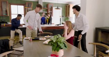 Mutfak adasında çeşitli arkadaşlar kutlama yapıyor, su dolduruyor, selfie çekiyor, hamur işleri kızartıyor. Sosyal toplantı, ev yemeği, çağdaş dekor, canlılık, yaşam tarzı, rahatlama, birliktelik.